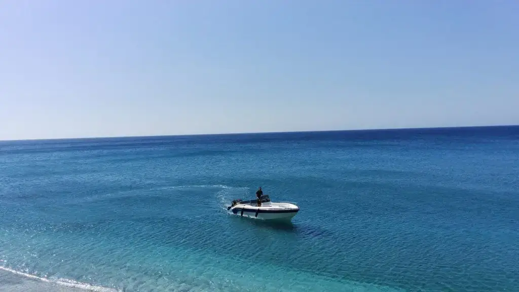 Aphrodite I boat with skipper driving towards the beach – Aphrodite Boat Rental Milos