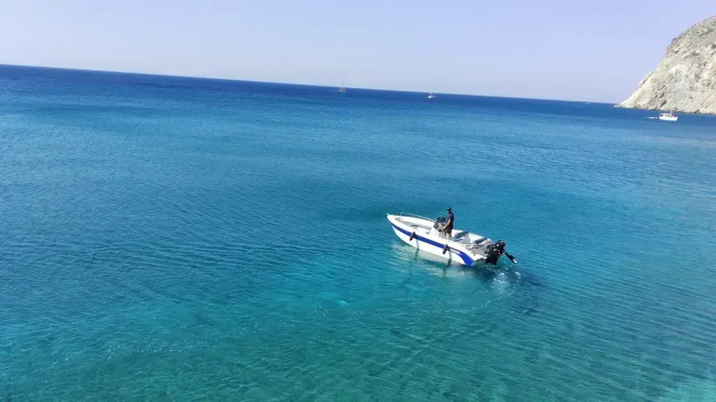 Aphrodite I boat with skipper driving away from the beach – Aphrodite Boat Rental Milos